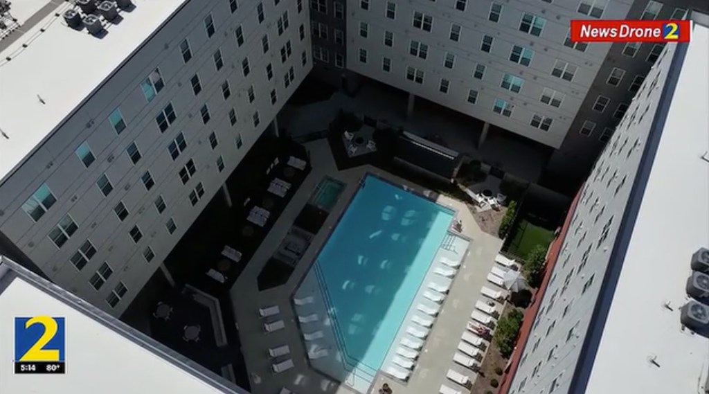 An aerial view of The Rambler apartment complex, showing a courtyard with a swimming pool surrounded by multi-story buildings.