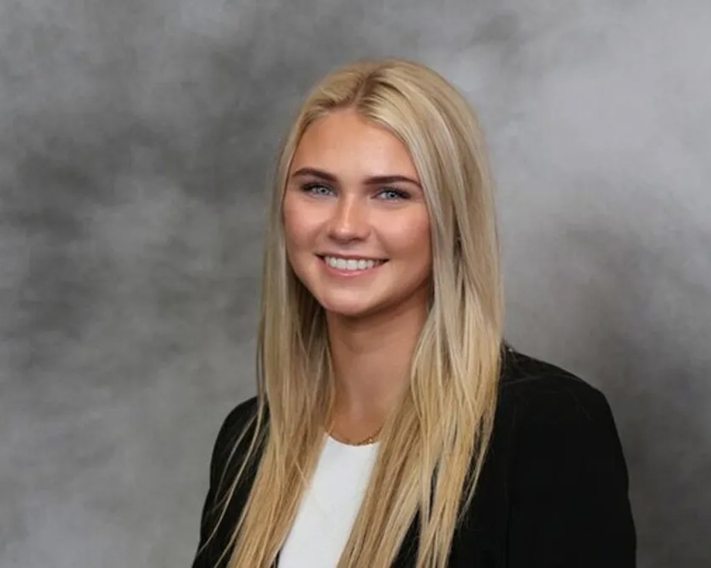 Portrait of Kristin Sargent smiling against a grey background.
