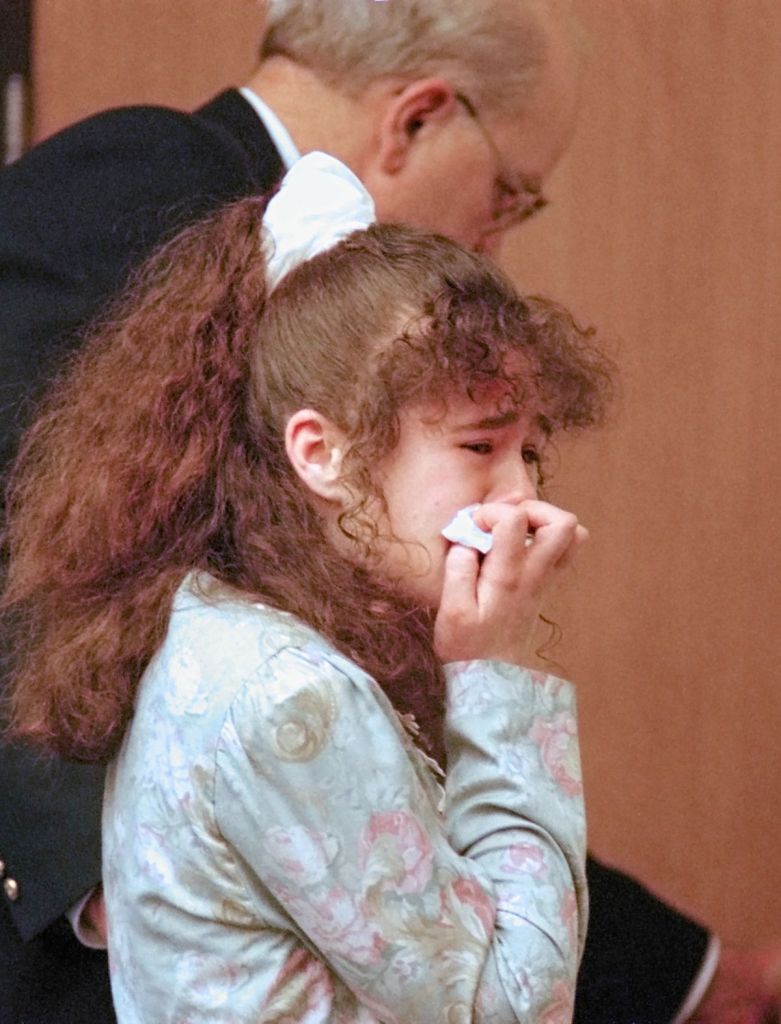 Christa Gail Pike crying and holding a tissue to her face, escorted after being sentenced to death.