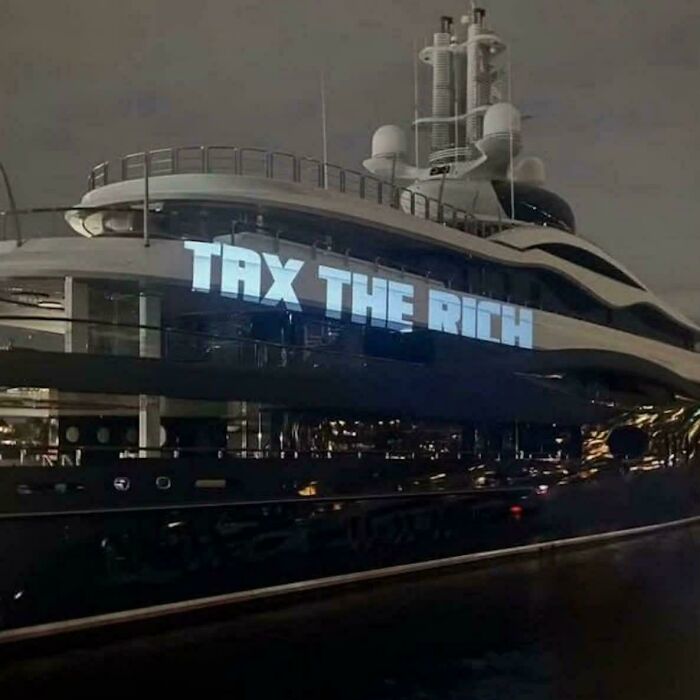 A luxury yacht with 'TAX THE RICH' projected onto its side, illustrating an 'Eat The Rich' moment. A luxury yacht with 'TAX THE RICH' projected onto its side, illustrating an 'Eat The Rich' moment.